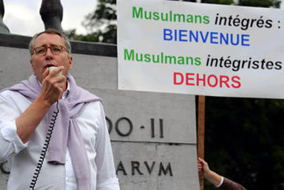 Mischaël Modrikamen, then leader of the Belgian People’s Party, speaking beside a sign in French that reads: “Integrated Muslims: Welcome; Fundamentalist Muslims: Out.”